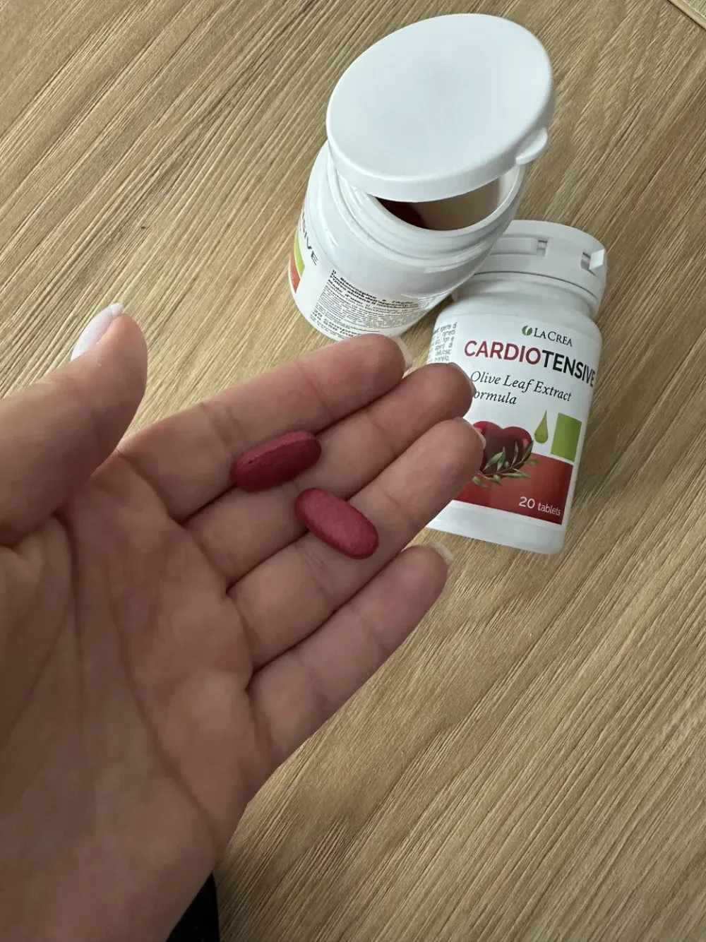 Flacone di Cardiotensive aperto con le compresse ovali rosso-bordeaux all’interno